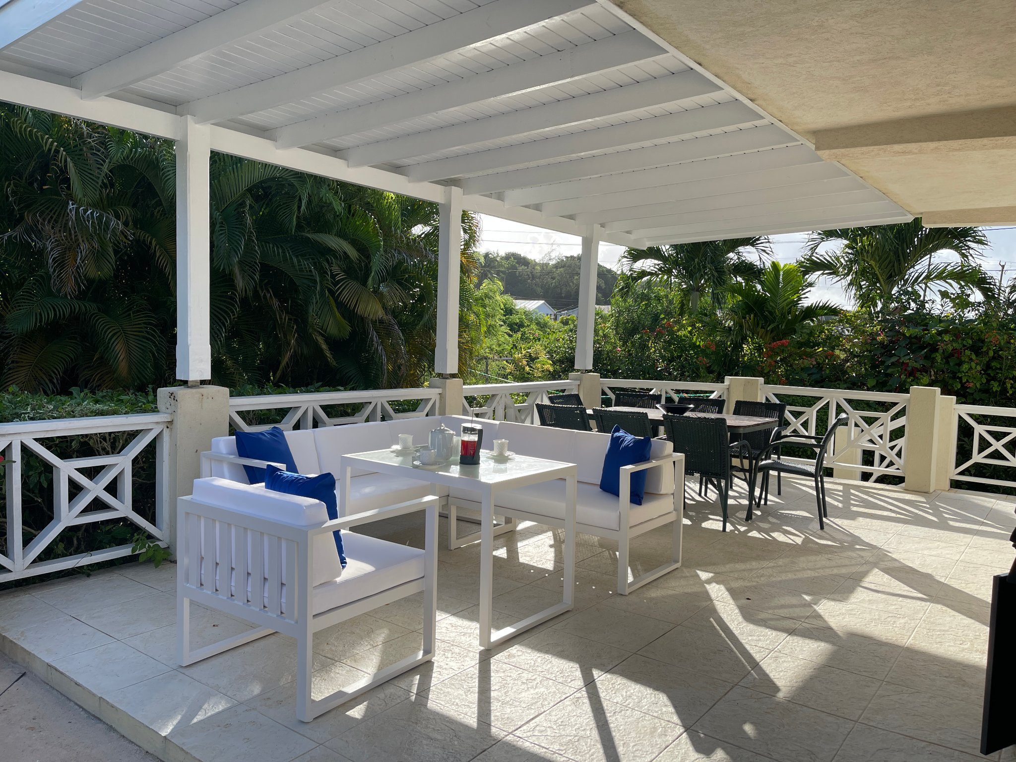 Holland Park Villa back terrace with white outdoor sofas, dining area and tropical garden views